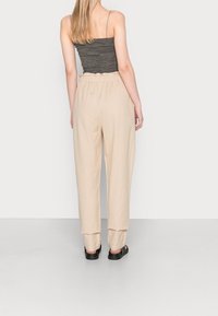Pantalon beige en mélange de lin à coupe décontractée, doté d'une taille élastique et de jambes fuselées, associé à un haut gris côtelé ajusté.