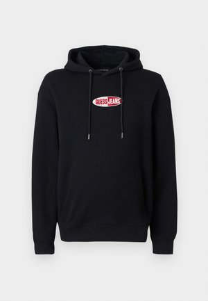 Črna kapuca iz bombažnega mešanega materiala, z žepom za roke in kapuco na vezalko. Logotip "GUESS JEANS" v rdeči in beli barvi na sprednji strani.