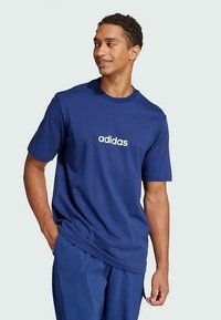 Kara zila kokvilnas T-kreklu ar apaļu kakla izgriezumu un īsām piedurknēm, ar baltu "adidas" logo centrā uz krūtīm. Gluda tekstūra.