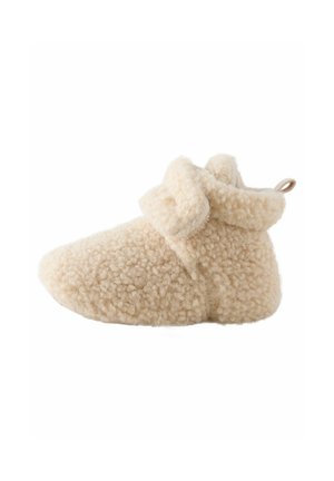 Beige fuzzy Hausschuh mit einer weichen, strukturierten Oberfläche, abgerundetem Zehenbereich und umgeschlagenem Bund. Verfügt über eine kleine Schlaufe für einfaches Anziehen.
