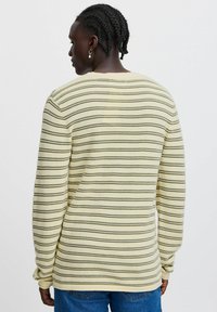 Striped long-sleeve sweater in pale yellow and dark green, featuring a relaxed fit, ribbed texture, and rounded neck.