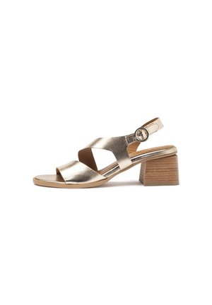 Gold leather open-toe sandal with crossed straps, adjustable ankle buckle, and low block wooden heel on white background.
