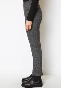 Grå byxor med hundtandsmönster och smal passform, med midja i normalhöjd och mjuk textur, kombinerade med svarta ankelstövlar.
