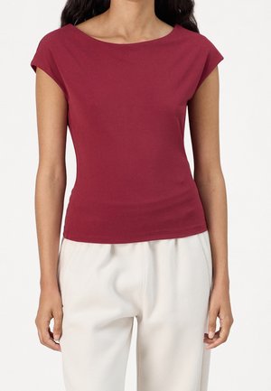 Top corto burdeos de manga corta con escote barco, tejido suave, diseño ajustado, combinado con pantalones sueltos color crema.