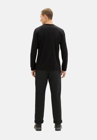 Zwarte lange mouwen shirt en zwarte broek, met een ontspannen pasvorm en een zachte textuur, met opgerolde mouwen op de broek en zonder zichtbare patronen.
