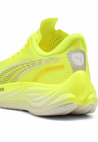 Scarpa da ginnastica gialla brillante con una tomaia in rete traspirante, dettagli texture e accenti bianchi. Presenta una suola imbottita e un tassello posteriore per facilitare la calzata.