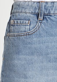 Shorts in denim azzurro chiaro con vita alta, tasche visibili, cuciture a contrasto e una texture leggermente sbiadita.