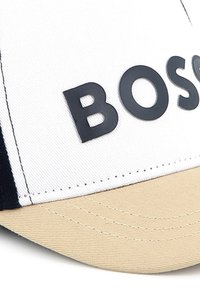 Witte pet met een beige klep, voorzien van een verhoogd zwart "BOSCO" logo aan de voorkant. Gelaagd stof met een gedetailleerd stikpatroon.