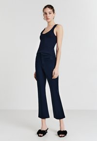 Canotta a coste blu navy abbinata a pantaloni larghi blu navy e pantofole nere pelose. L'outfit presenta una silhouette aderente e texture morbide.