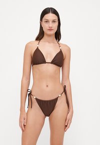 Ensemble de bikini marron comprenant un haut triangulaire avec des liens réglables et des perles décoratives, accompagné d'un bas à liens sur les côtés. Texture lisse.