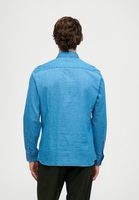 Camicia a maniche lunghe azzurro chiaro realizzata in un tessuto testurizzato, dotata di colletto, polsini con bottoni e orlo curvo con una vestibilità rilassata.