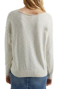 Jasno beżowy sweter z dzianiny o szerokim dekolcie typu off-the-shoulder oraz prążkowanym wykończeniu. Tkanina ma miękką, fakturowaną powierzchnię.