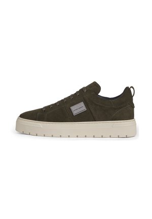 Low-top dark green suede sneaker with thick white sole, matching laces, and a small rectangular metal logo plaque on the side.