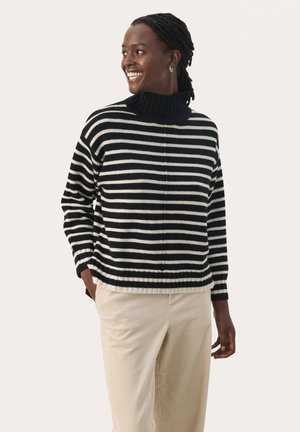 Pull en noir et blanc à rayures avec un col côtelé haut. Fabriqué en maille, il présente une coupe ample et un ourlet côtelé. Associé à un pantalon en velours côtelé beige.