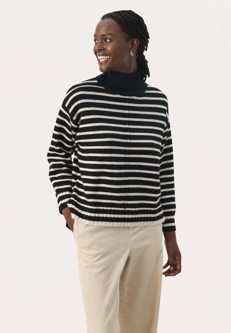 Zwart-wit gestreepte sweater met een hoge ribgebreide kraag. Gemaakt van gebreid materiaal, met een losse pasvorm en ribgebreide zoom. Gecombineerd met beige corduroybroek.