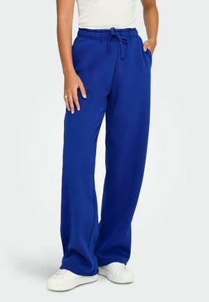Blå bomulds sweatpants med en afslappet pasform, snøre-i-livet og sidelommer, parret med hvide sneakers.