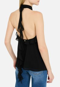 Top halter nero in tessuto leggero, con design senza schiena, dettagli a volant lungo i lati e una chiusura a bottone in vita.