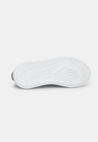 Suela de zapatilla de goma blanca con un patrón de textura en la suela, que presenta un emblema circular en la parte inferior y un sutil logotipo de la marca.