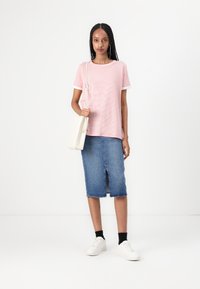 Pink and white striped t-shirt, paired with a knee-length denim skirt featuring a front slit. White sneakers and a cream crossbody bag.