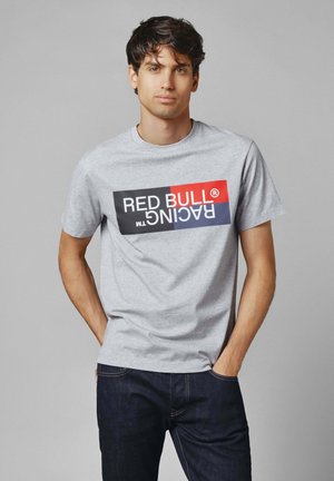 Grå bomulds t-shirt med "RED BULL RACING" logo i rød og sort print på forsiden, parret med mørke denim jeans.
