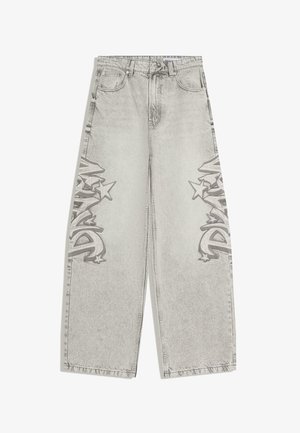 Jasnoszare dżinsy o szerokich nogawkach z przednimi kieszeniami i ciemnymi, graffiti w stylu gwiazdy na zewnętrznych stronach ud.