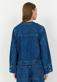 Denim jakna v temno modri barvi, s klasičnim krojem, gumbnimi manšetami in žepom z izvezenim logotipom na hrbtu.