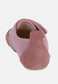 Różowy but wykonany z zamszu i materiału, zaokrąglony z tyłu, z wyściełanym kołnierzem. Posiada delikatne przeszycia i teksturowaną podeszwę.