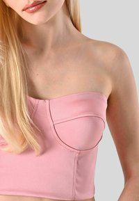 Top senza spalline rosa con un tessuto strutturato e liscio, caratterizzato da coppe sagomate e una silhouette aderente. Nessun dettaglio o abbellimento aggiuntivo.