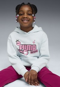 Ljusblå hoodie med rosa Hello Kitty-tryck, med en känguruficka. Kombinerad med lila byxor och håraccessoarer av klara pärlor.