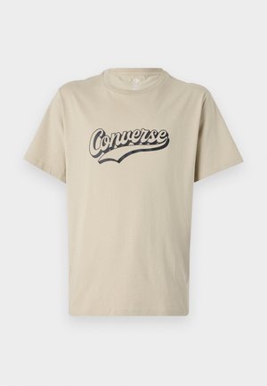 Beige katoenen t-shirt met een zwart "Converse" logo in een gebogen lettertype ontwerp aan de voorkant. Korte mouwen en een ronde halslijn.