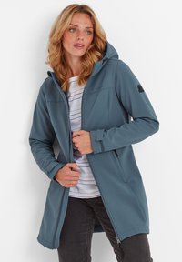 Softshell jacket in teal with a hood, front zip closure, zippered pockets, and a lightweight design. Features a striped shirt underneath.