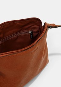 Sac en cuir marron avec une fermeture éclair et une poche intérieure. Texture lisse, forme structurée et doublure en tissu durable.