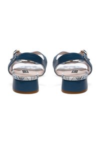 Sandales en cuir bleu avec une boucle, dos fermé et semelle intérieure à motifs blancs. Elles possèdent un petit talon cylindrique et un fini lisse.