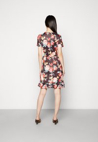 Vestido floral em tecido escuro; apresenta mangas curtas, um cinto na cintura e uma bainha com pregas. Inclui padrões florais em rosa, vermelho e azul.
