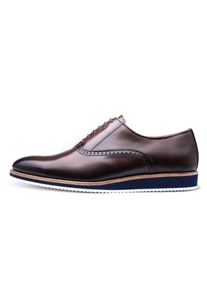 Bruine leren nette schoen met brogue-details, ronde neus, lichtblauwe veters en een witte rubberen zool met blauwe accenten.