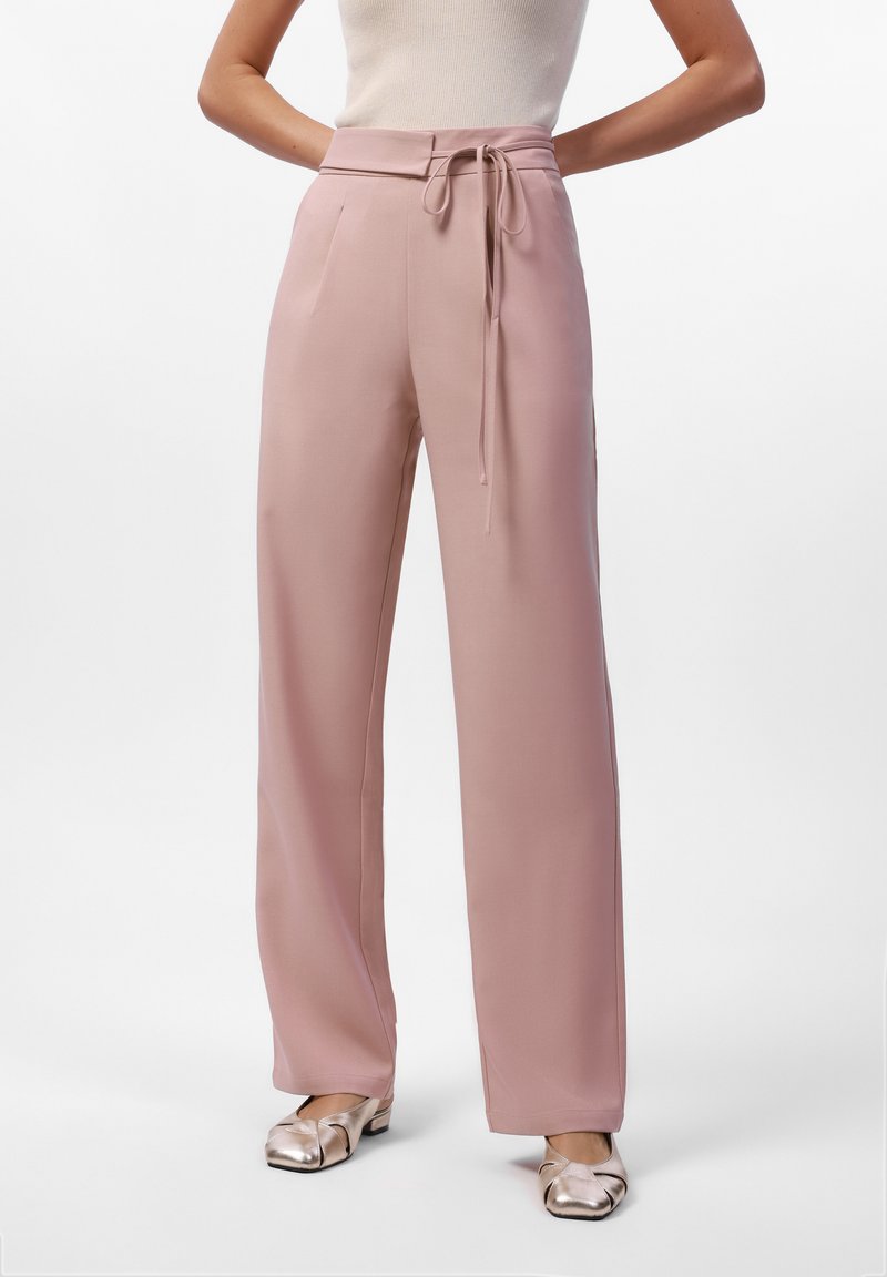Lichtroze wijde broek van soepel materiaal; heeft een hoge taille met een strikceintuur en zijzakken. Gekocht met metallic flats.