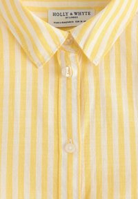 Gul og hvid stribet skjorte med knap-front, krave og let tekstureret stof. Etiket viser mærke og lavet i Bangladesh.
