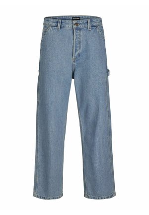 Chemise blanche à manches longues avec texte et graphiques noirs sur les manches, accompagnée d'un jean bleu ample et de baskets grises. Tenue décontractée.