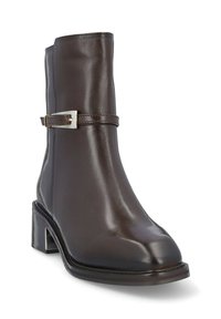 Bota de cuero marrón hasta el tobillo con una punta redonda, pequeño tacón cuadrado y una correa decorativa con un detalle de hebilla plateada. Acabado suave y pulido.