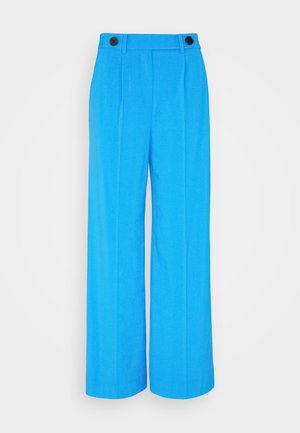 Erksin sinised laiad püksid teravate eesrihmadega, kaks musta nööbi vöökoha juures ja sile kangatekstuur.