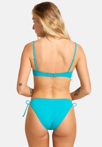 Set di bikini turchese con un design minimalista, spalline regolabili e laccetti laterali sul fondo, realizzato in materiale liscio e elastico.