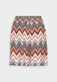 Shorts amples à taille élastique, présentant un motif zigzag multicolore en nuances de marron, noir, blanc, rose et bleu sur fond blanc.
