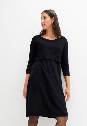 Schwarzes Kleid mit dreiviertel Ärmeln, rundem Ausschnitt und tailliertem Oberteil, das in einen lockeren Rock übergeht; strukturierter Stoff mit dezentem Glanz.