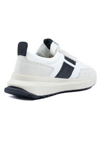 Weiße und graue Sneakers mit einem Obermaterial aus Wildleder und Leder, ausgestattet mit einem schwarzen Akzent und einer strukturierten Gummisohle, die für Komfort ausgelegt sind.