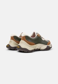 Sneaker in pelle verde e marrone con suola beige chiara, dettagli testurizzati e design arrotondato. Presenta una suola esterna in gomma nera a contrasto.