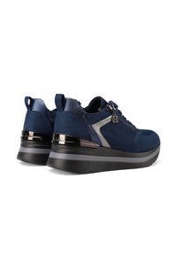 Un paio di sneaker platform blu navy con suole spesse nere e grigie, cerniera laterale, linguette per il piede e dettaglio metallico sul tallone, viste da un'angolazione posteriore.