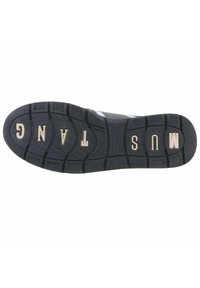 Semelle de chaussure en caoutchouc noir avec un motif texturé, comportant des lettres en relief épelant "MUSTANG". Le design inclut des rainures profondes pour l'adhérence.