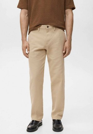 Beige cotton pants with a straight-leg design, featuring a classic waistband and simple front pockets. Worn with black shoes and a brown top.