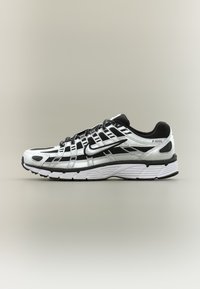 Λευκό και μαύρο αθλητικό παπούτσι Nike P-6000 με ανώτερο μέρος από δίχτυ και συνθετικό υλικό, κλείσιμο με κορδόνια και χοντρή λευκή σόλα, πάνω σε ουδέτερο φόντο.