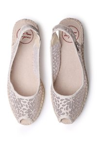 Light beige espadrilles with an open toe, featuring floral lace overlay, fabric lining, and woven jute soles. Subtle texture and detailing.